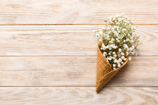 Waffle cone with beautiful gypsophila flowers on color background. summer concept. Copy space top view. - Fotó, kép