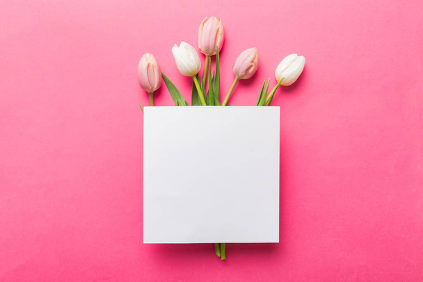 Összetétel üres kártyával és gyönyörű virágokkal tulipán színes háttérrel. top view helyet az Ön számára desing. - Fotó, kép
