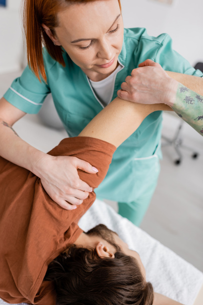 thérapeute manuel étirement bras douloureux de l'homme pendant le traitement dans le centre de réadaptation - Photo, image