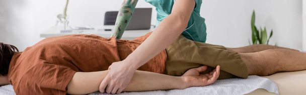 vista parcial del especialista en rehabilitación haciendo masaje para aliviar el dolor al hombre en el centro de rehabilitación, pancarta - Foto, Imagen