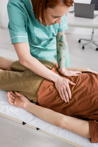 manual therapist massaging painful back of man in recovery center - Photo, Image