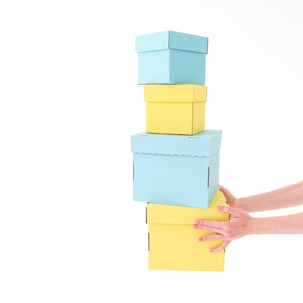 Yellow and blue boxes hold their hands on a white background. Place for text and logo. The concept of packaging, gift, delivery. High quality photo - 写真・画像