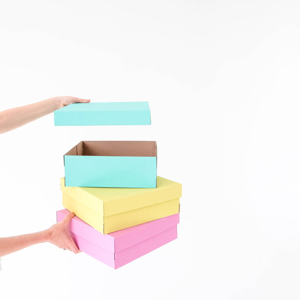 Colored boxes are held and opening on a white background. There is space for text. The concept of packaging, gifts, moving, training. High quality photo - Photo, Image