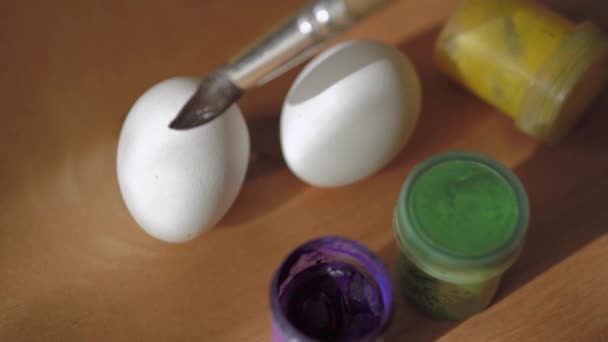 αυγά κοτόπουλου και χρώματα με ένα πινέλο σε μια ξύλινη επιφάνεια. Πάσχα. ψυχαγωγία των παιδιών - Πλάνα, βίντεο