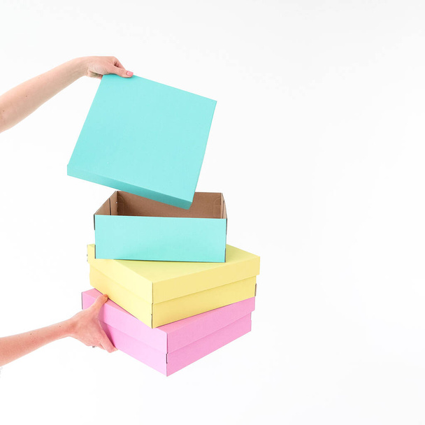 Colored boxes are held and opening on a white background. There is space for text. The concept of packaging, gifts, moving, training. High quality photo - Fotografie, Obrázek