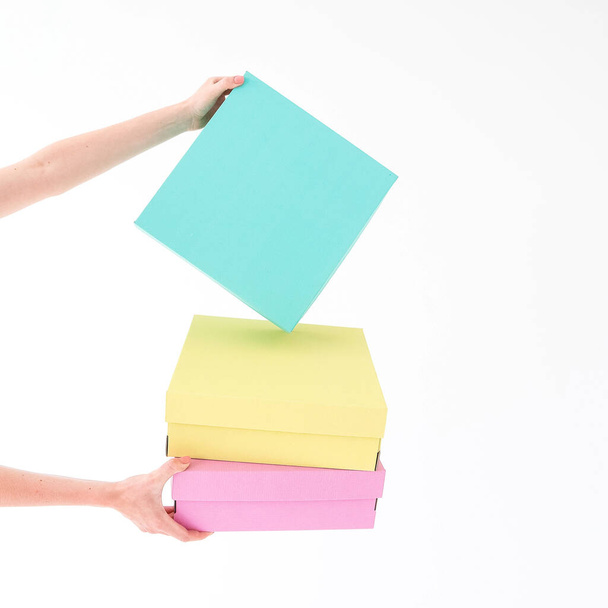 Colored boxes are held on a white background. There is space for text. The concept of packaging, gifts, moving, training. High quality photo - Foto, Imagem