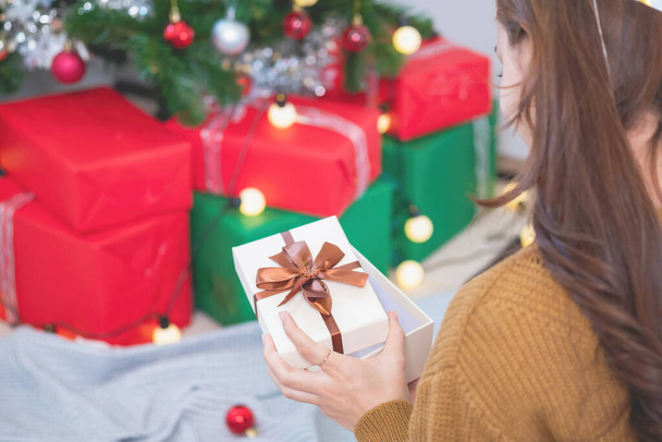 Mutlu Noeller ve mutlu tatiller! Sarı gömlekli güzel yüzlü genç bir kadın Noel ağacı süslenmiş bir evde hediye kutularıyla neşe gösteriyor. Xmas 'tan Önce Portre - Fotoğraf, Görsel