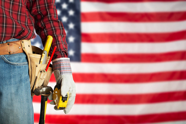 Laborer in gloves and toolbelt with measure on us flag background labor day mockup - Valokuva, kuva