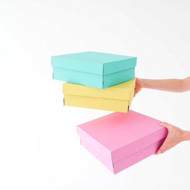 Colored boxes are held and opening on a white background. There is space for text. The concept of packaging, gifts, moving, training. High quality photo - Zdjęcie, obraz