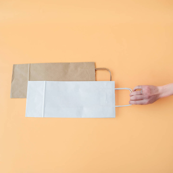 Craft long packaging bags on an orange background. Place for text and logo. The concept of packaging, gift, drink, bottle packaging. High quality photo - Foto, imagen