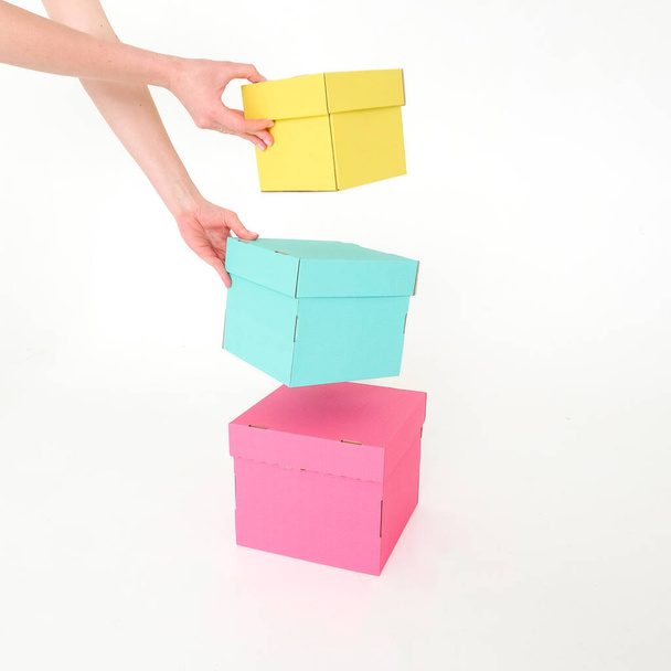 Craft boxes are yellow, green and pink, held by a human hand on a white background. Place for text and logo. The concept of packaging, packaging, uniform style, branding, holiday, gifts. High quality photo - 写真・画像