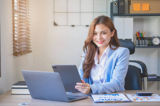 Marketing, finance, accounting, planning, female accountant portrait with beautiful smile wearing team blue suit using laptop calculator and documents, charts, graphs In the company analysis is profit - Photo, Image