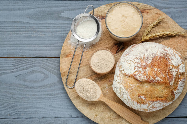 Freshly baked bread, sourdough and flour on grey wooden table, top view. Space for text - Foto, Imagen