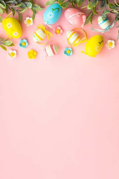 Easter background with holiday decorations. Eggs, spring leaves and flowers on pink. Flat lay with copy space. - Фото, зображення