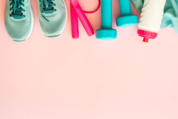 Fitnesstoestellen op roze achtergrond. halters, handdoek en een fles water. Trainings-, workout- en fitnessconcept. - Foto, afbeelding