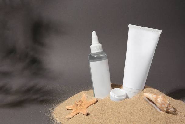Cosmetic products, starfish and seashell on sand against grey background. Space for text - Photo, image