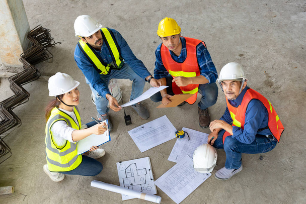 Top view of engineer, architect, contractor and foreman meeting at the construction building site with floor plan for real estate development project industry and housing inspection timeline usage - Foto, immagini