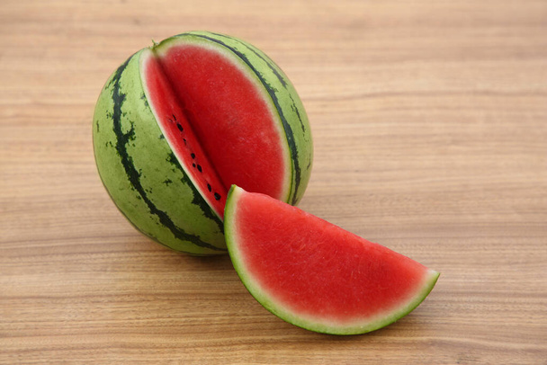 Cut delicious ripe watermelon on wooden table - Fotoğraf, Görsel