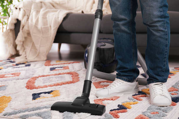Man cleaning carpet with vacuum cleaner at home, closeup - Foto, imagen