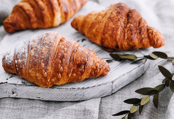 Close up three freshly baked croissants with sugar powder on a wooden desk - Photo, Image