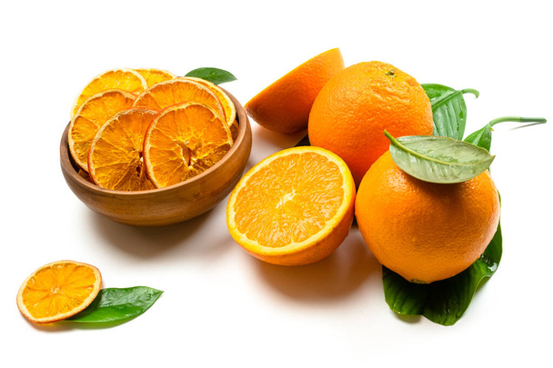 Droge sinaasappelschijfjes en vers fruit op witte ondergrond. Gedehydrateerde snacks van sinaasappelfruit. Gezond, geen suiker zoet voedsel. gekonfijte citrusvruchten - Foto, afbeelding