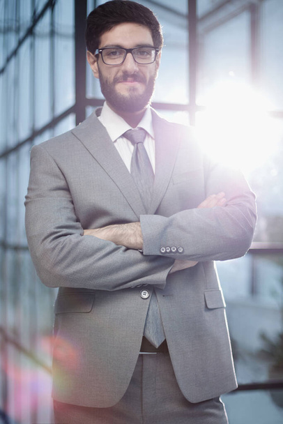 Уверенный мужчина-бизнесмен, стоящий в современном офисе. - Фото, изображение
