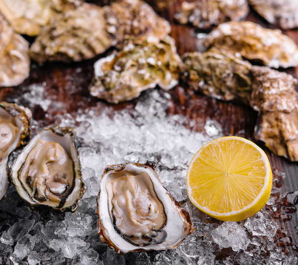 Opened oysters, ice and lemon on board - Foto, imagen