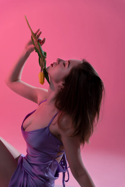 Woman in studio with flowers on beautiful pink background - Фото, зображення