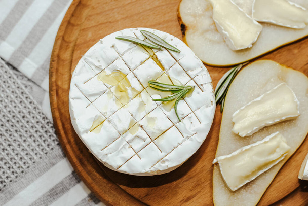 Λευκή μπαγκέτα κομμένη σε κομμάτια με ελαιόλαδο και τυρί Camembert στο τραπέζι. - Φωτογραφία, εικόνα