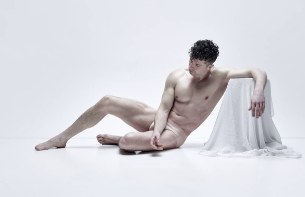 Art of human being. Muscular mature man posing shirtless in underwear against white studio background with fabric elements. Concept of male body aesthetics, mens beauty, inspiration, art - Foto, Imagem