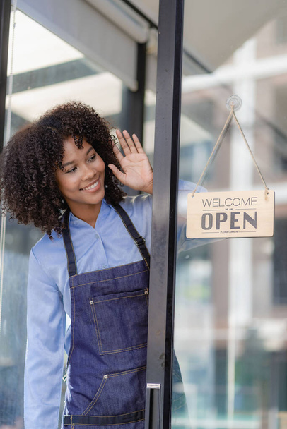Barista Startup Coffee Shop Entrepreneur African American Woman Standing at the Door of a Casual Coffee Shop Showing an Open Sign Happy and cheerful smile with service, food and drink concept - Foto, immagini