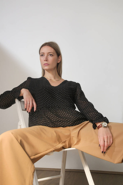 Serie of studio photos of young female model in elegant viscose v neck blouse and beige trousers - Fotó, kép
