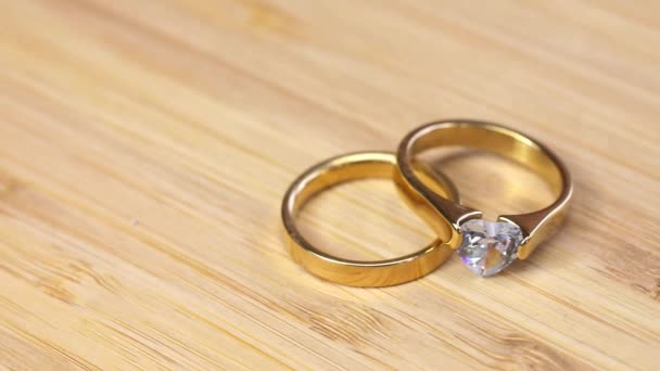 Bagues d'or de mariage avec diamant sur fond de table en bois. Images de bijoux pour le mariage avec espace de copie, bagues de fiançailles or étincelant - Séquence, vidéo