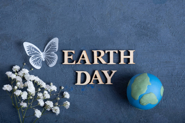 Text zum Tag der Erde mit Globus, Blumen und Schmetterling. Happy Earth Day Konzept flach gelegt, Draufsicht. - Foto, Bild
