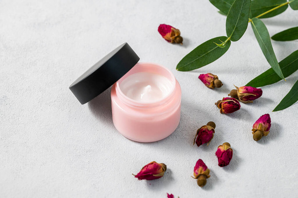Face or body cream with rose  on a light background. The concept of care cosmetics with herb eucalyptus. Health and beauty. Copy space. - Photo, Image