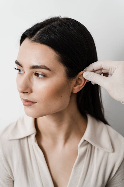 Операция на ухе. Отопластическая хирургическая перестройка вышивания и уха. Хирург осматривает женские уши перед топластикой косметической хирургии - Фото, изображение