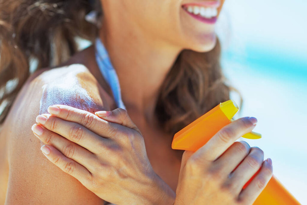 Closeup on smiling young woman applying sun block creme - 写真・画像