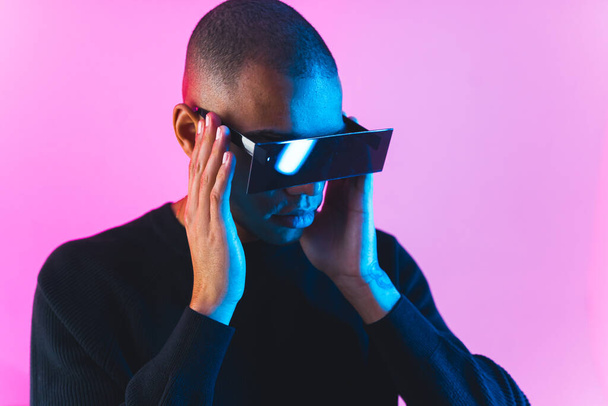 A man wearing VR goggles in cyberpunk light tones studio . High quality photo - Fotografie, Obrázek