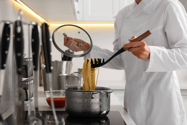 Professional chef cooking delicious pasta in saucepan indoors, closeup - Foto, imagen
