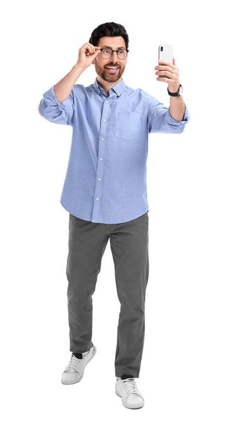Smiling man taking selfie with smartphone on white background - Foto, Imagen
