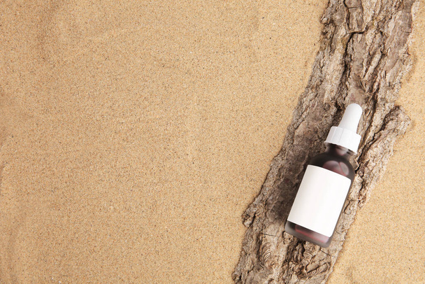 Bottle with serum and bark on sand, top view with space for text. Cosmetic product - Valokuva, kuva