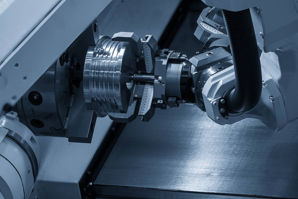 Automatyczne ramię robota chwytającego metalowe części z tokarki CNC. Zaawansowany technologicznie proces przenoszenia materiału przez system robotyczny w tokarce.  - Zdjęcie, obraz