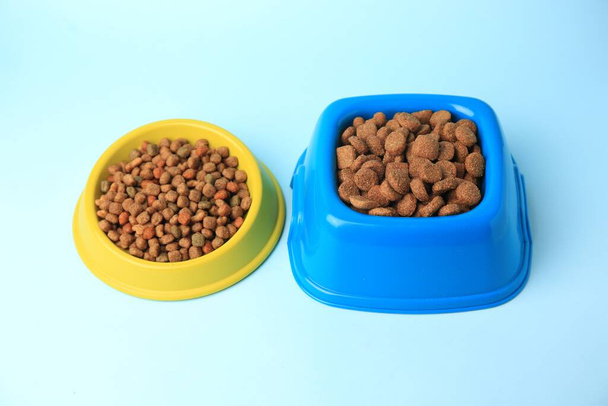 Dry pet food in feeding bowls on light blue background - Foto, immagini