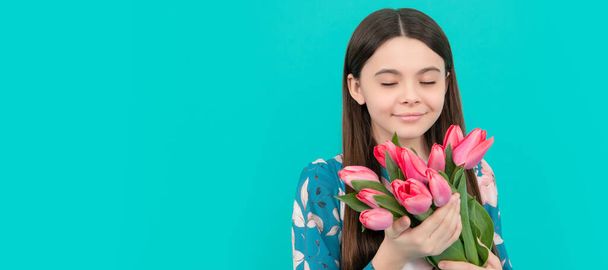 kid hold flowers for 8 of march. teen girl with spring bouquet on blue background. Banner of spring child girl with tulips flowers bouquet, studio portrait with copy space - Fotó, kép