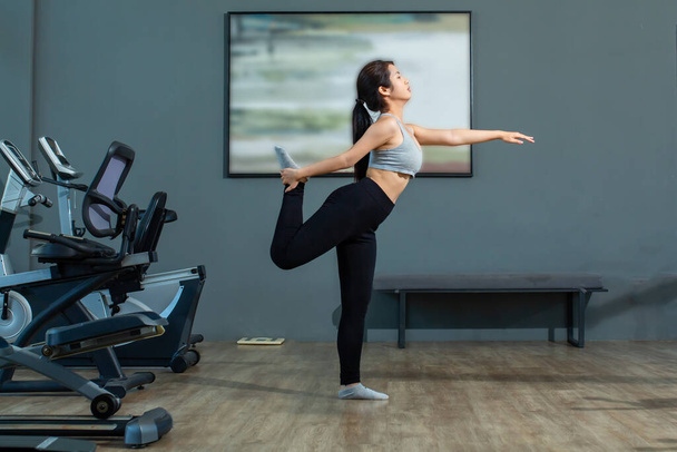 Красива молода азіатська дівчина носить тренувальний одяг і займається вправами йоги у фітнес-центрі
. - Фото, зображення
