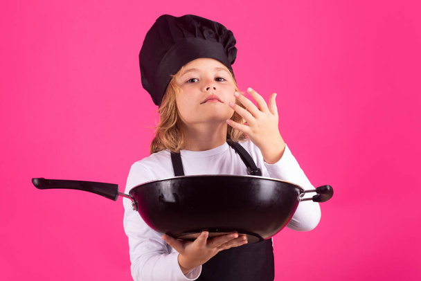 Chef cuisinier enfant avec poêle. Enfant en uniforme de cuisinier. Chef gamin isolé sur fond rose. Enfant mignon pour être un chef. Enfant habillé comme un chapeau de chef - Photo, image