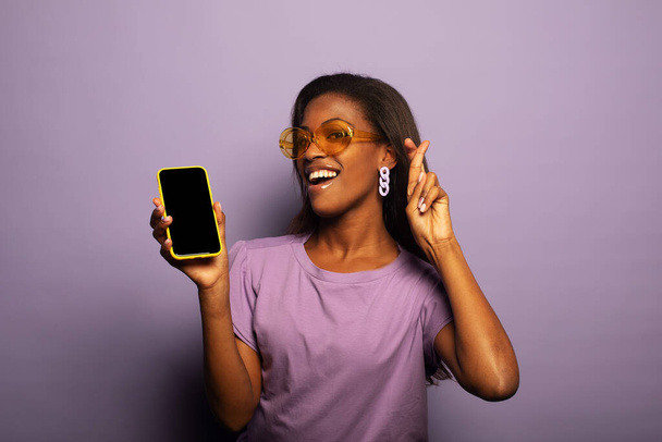 lifestyle, tehnology and people concept: Portrait of inspired dreamy american young surprised woman use her smartphone, model female over purple color bacjground. - Foto, Bild