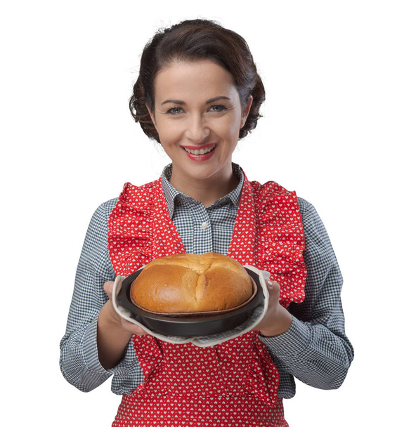 Smiling vintage woman holding an homemade cake in a baking tin - Photo, Image