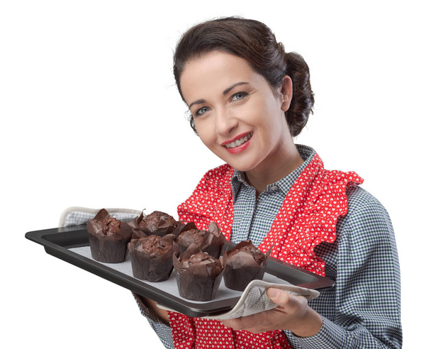 Smiling vintage woman holding a baking tray with chocolate home made muffins - Fotografie, Obrázek