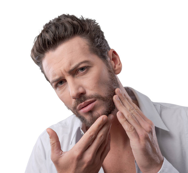 Young handsome man checking his face skin and touching his beard - Foto, immagini